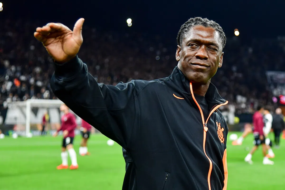 Clarence Seedorf steekt zijn hand op langs het veld voor een voetbalwedstrijd.