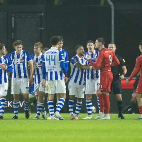Spelers van FC Eindhoven en Helmond Sport staan dicht bij elkaar tijdens een verhitte fase in een voetbalwedstrijd.