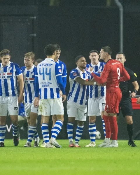 Spelers van FC Eindhoven en Helmond Sport staan dicht bij elkaar tijdens een verhitte fase in een voetbalwedstrijd.
