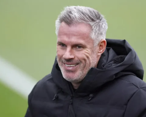 Jamie Carragher glimlacht tijdens een interview op een voetbalveld.