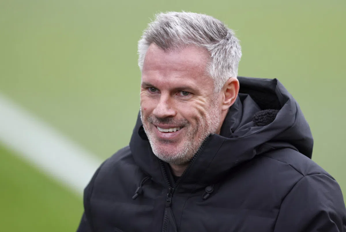 Jamie Carragher glimlacht tijdens een interview op een voetbalveld.