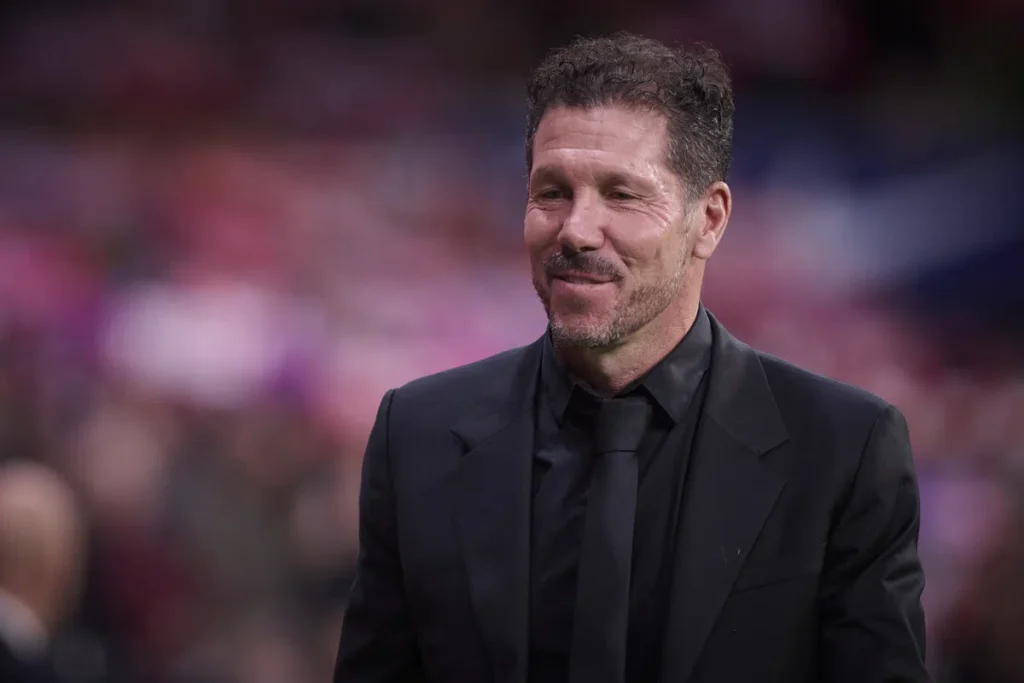 Diego Simeone staat in een zwart pak langs het veld in een stadion.