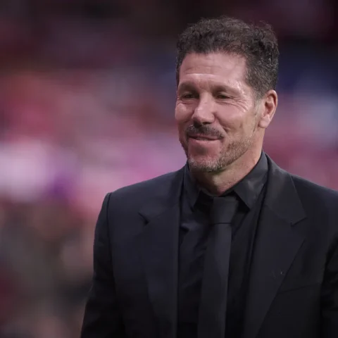 Diego Simeone staat in een zwart pak langs het veld in een stadion.