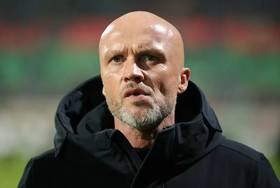Dick Schreuder staat langs het veld in een zwarte jas.