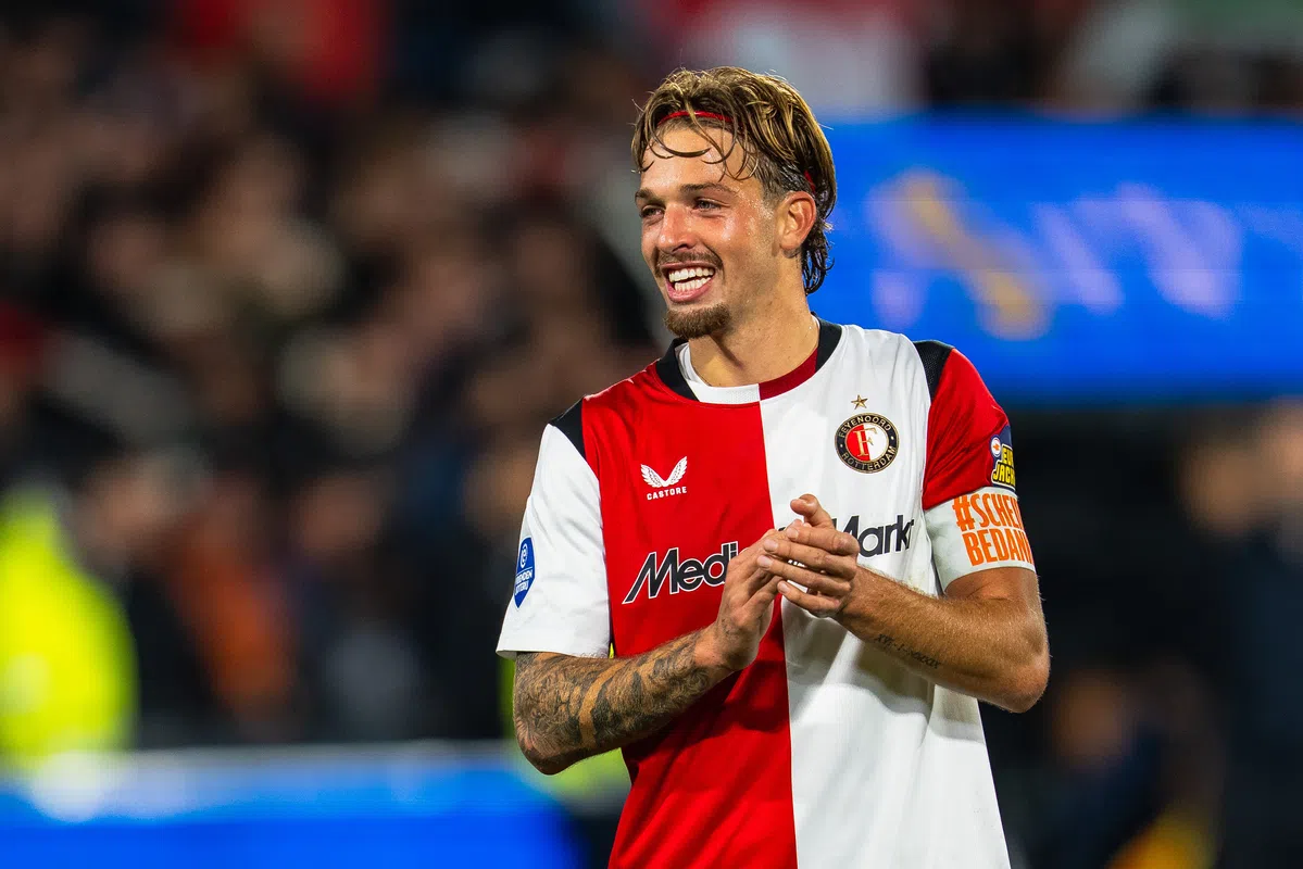 Feyenoord-speler in rood-wit tenue op het veld, klappend en lachend.