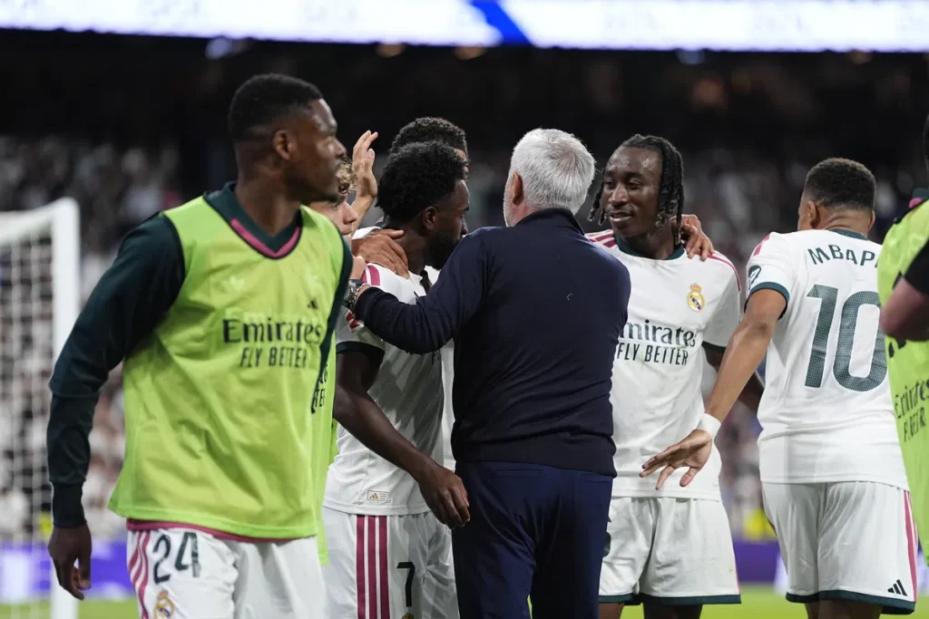Real Madrid-spelers en een staflid praten op het veld tijdens een wedstrijd.