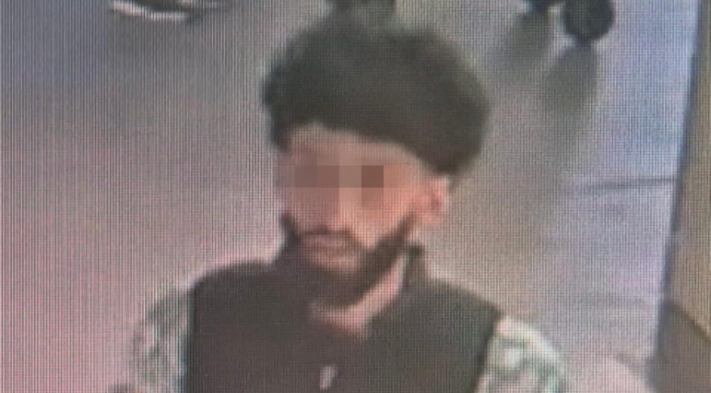 Wazige beveiligingsfoto van een man met donker haar en baard.