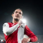 Feyenoord-speler in rood-wit shirt onder stadionlichten tijdens de wedstrijd.