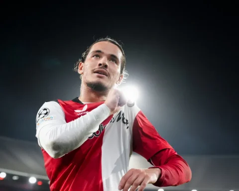 Feyenoord-speler in rood-wit shirt onder stadionlichten tijdens de wedstrijd.