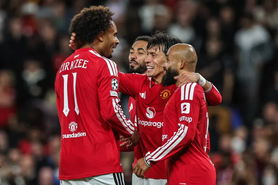 Manchester United-spelers vieren een moment op het veld in rode shirts.