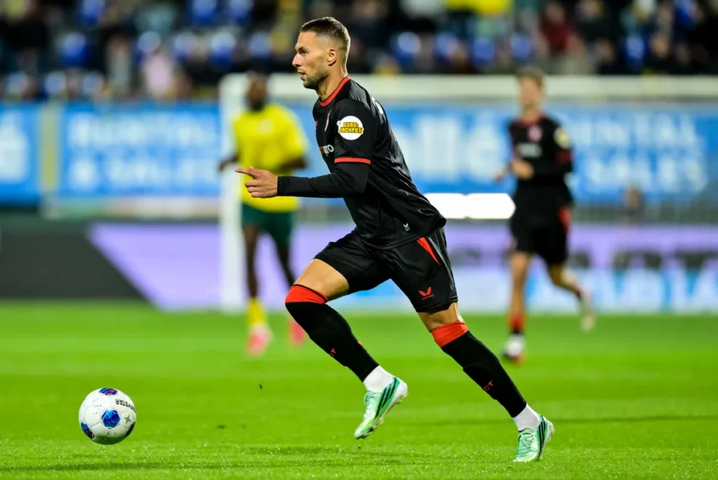 Marko Pjaca in een zwart FC Twente-shirt dribbelt over het veld tijdens een voetbalwedstrijd.