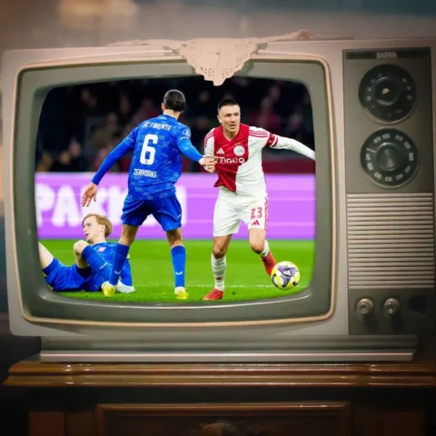 Oude televisie waarop een voetbalwedstrijd te zien is, met spelers van FC Twente en Ajax in beeld.