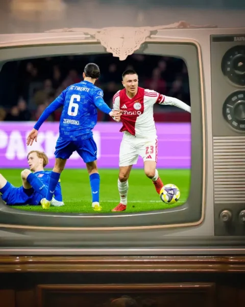 Oude televisie waarop een voetbalwedstrijd te zien is, met spelers van FC Twente en Ajax in beeld.