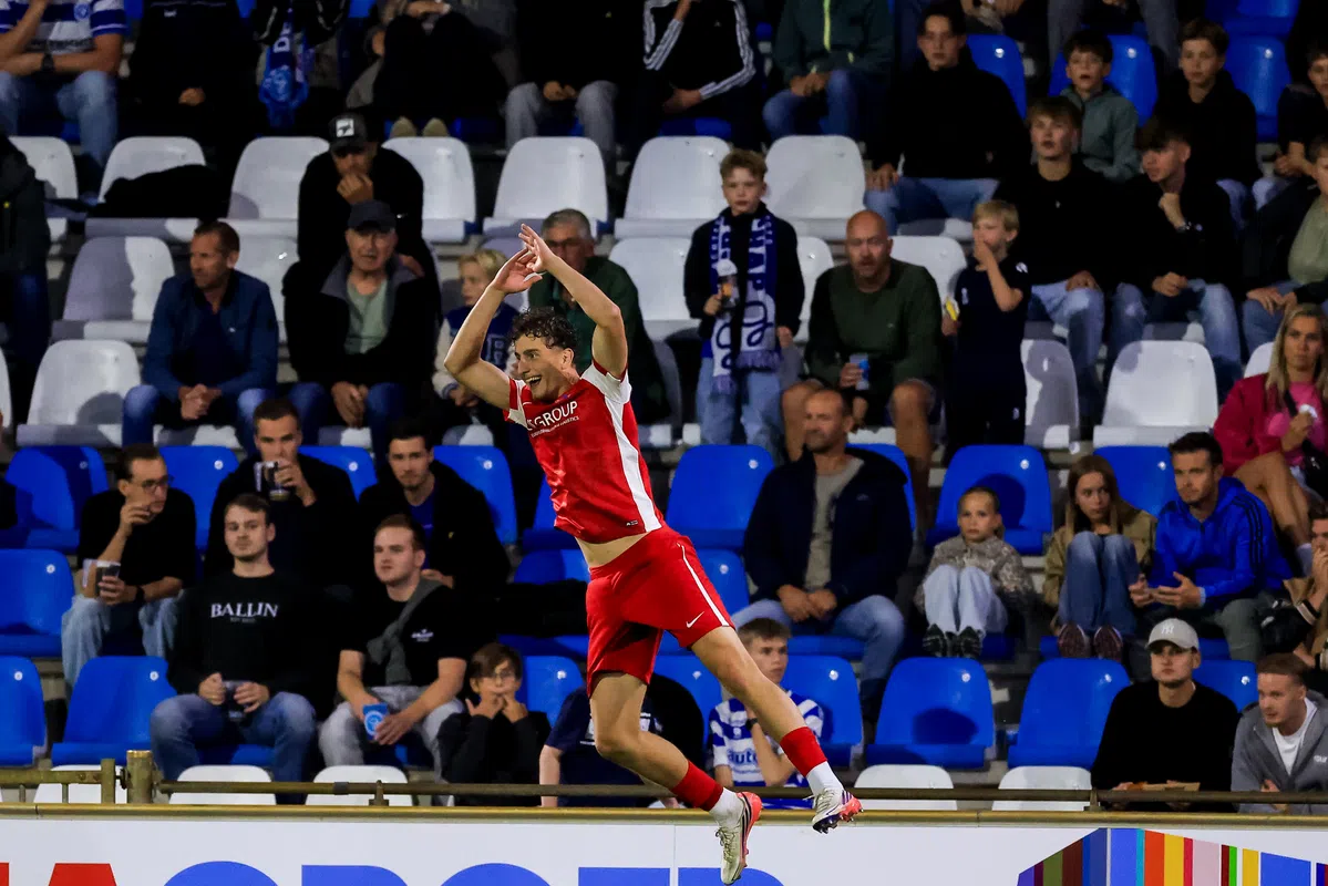 Voetballer in rood-wit juicht voor het publiek in een stadion.