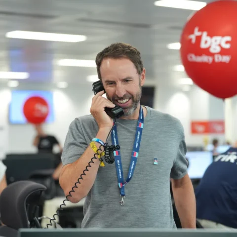 Gareth Southgate spreekt aan een telefoon in een kantooromgeving tijdens een BGC Charity Day.