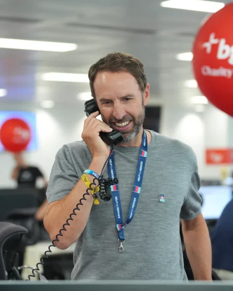 Gareth Southgate spreekt aan een telefoon in een kantooromgeving tijdens een BGC Charity Day.