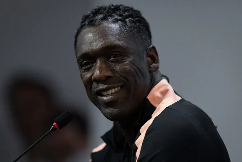 Clarence Seedorf spreekt bij een microfoon en kijkt naar de camera.