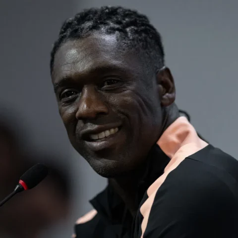 Clarence Seedorf spreekt bij een microfoon en kijkt naar de camera.
