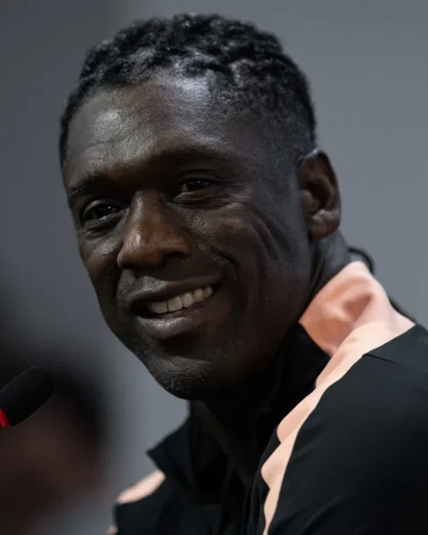 Clarence Seedorf spreekt bij een microfoon en kijkt naar de camera.
