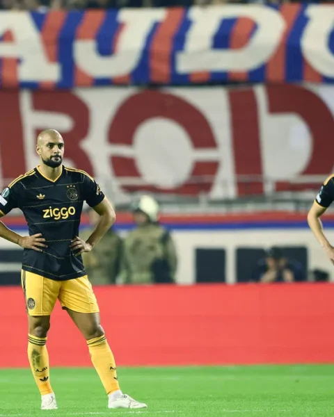 Twee Ajax-spelers staan teleurgesteld op het veld tijdens een wedstrijd.