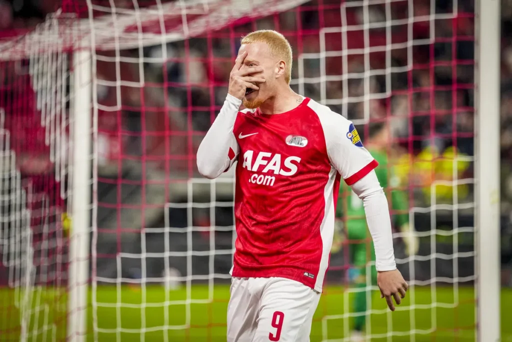 AZ-speler in rood-wit shirt bij het doel na een gemiste kans.