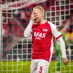 AZ-speler in rood-wit shirt bij het doel na een gemiste kans.