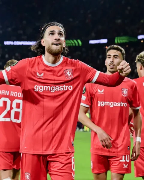 FC Twente-spelers vieren een doelpunt op het veld in een vol stadion.