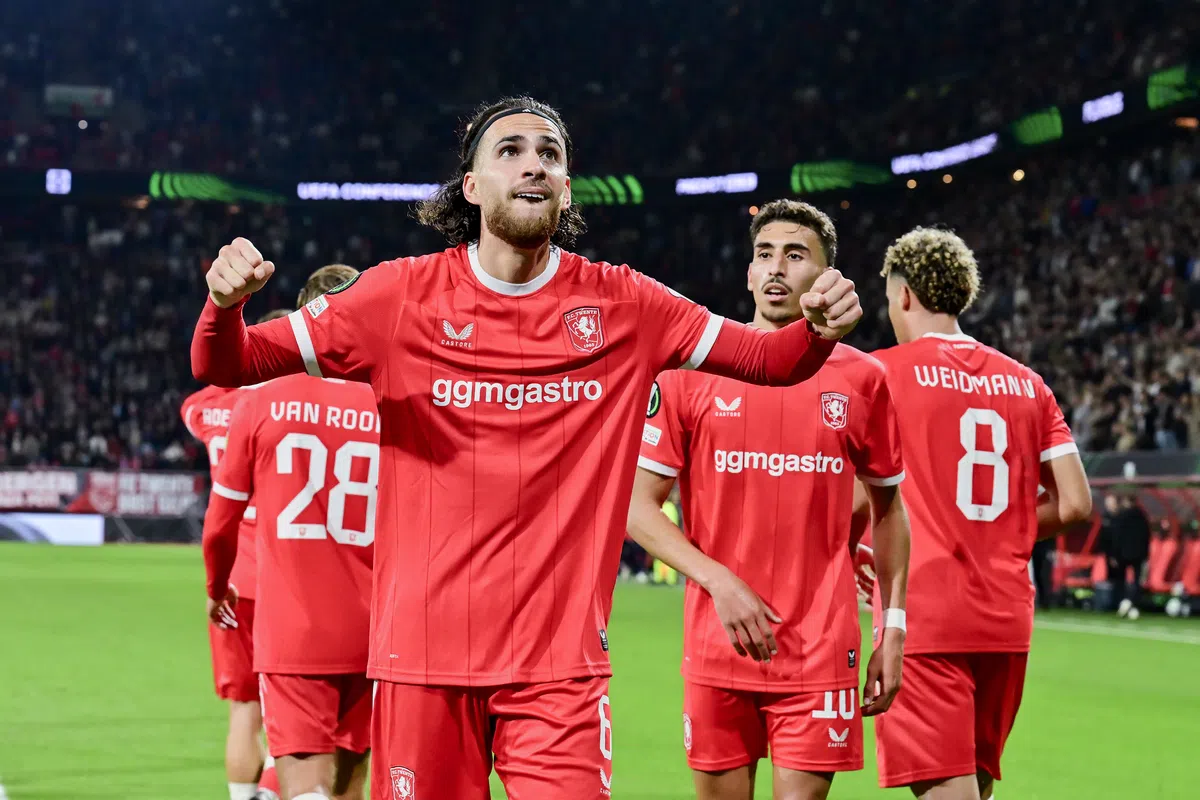 FC Twente-spelers vieren een doelpunt op het veld in een vol stadion.