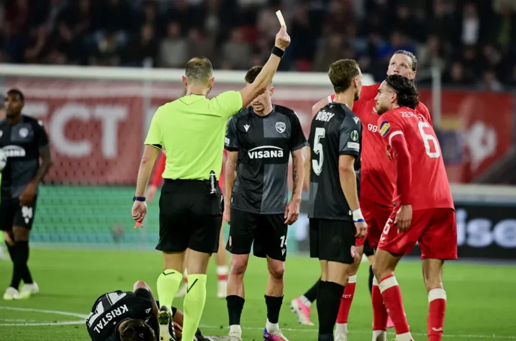Scheidsrechter toont een rode kaart tijdens FC Twente-FC Thun, terwijl spelers van beide teams rond hem staan.