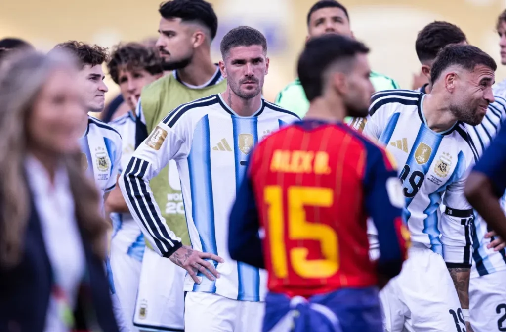 Rodrigo De Paul staat tussen andere Argentijnse voetballers in een wedstrijdomgeving.