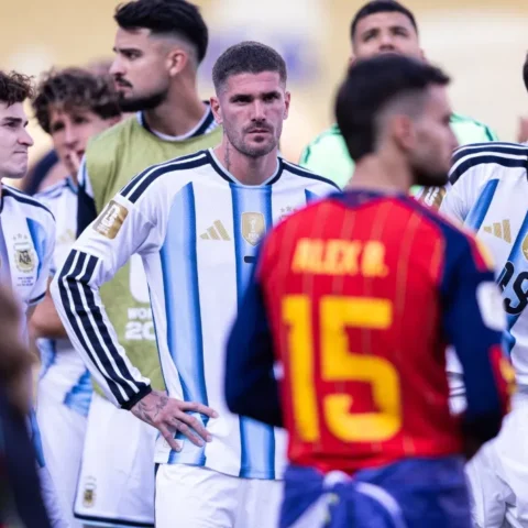 Rodrigo De Paul staat tussen andere Argentijnse voetballers in een wedstrijdomgeving.