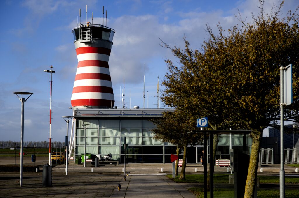 Luchthavengebouw met rood-witte verkeerstoren bij Lelystad Airport.