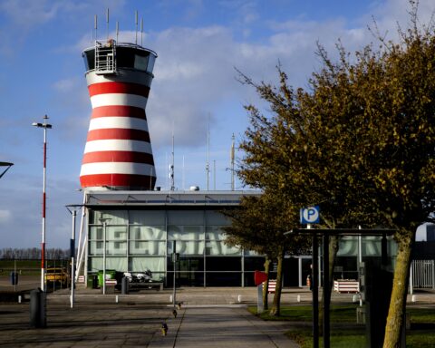 Luchthavengebouw met rood-witte verkeerstoren bij Lelystad Airport.
