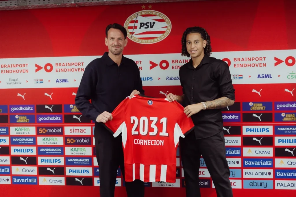 Shuryjano Cornecion poses with a PSV shirt showing 2031 during a contract presentation.