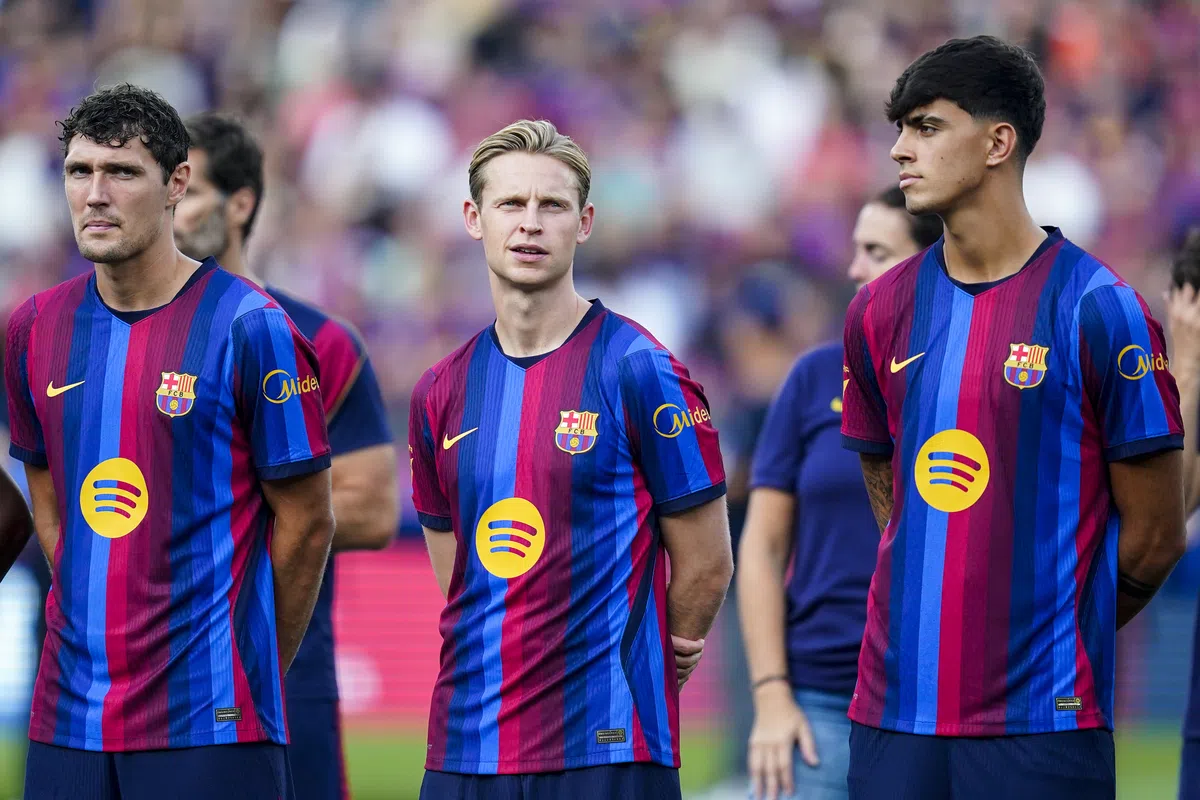 Frenkie de Jong staat tussen Barcelona-teamgenoten op het veld in het stadion.