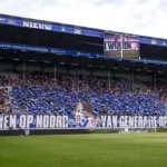 Supporters van SC Heerenveen in een vol vak in het Abe Lenstra Stadion met blauwe spandoeken en vlaggen.