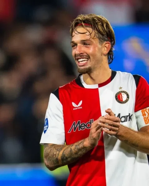 Luciano Valente in het shirt van Feyenoord tijdens een wedstrijd, lachend op het veld.