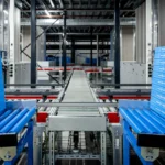 Blauwe Albert Heijn-bakken op een geautomatiseerde transportband in een distributiecentrum.