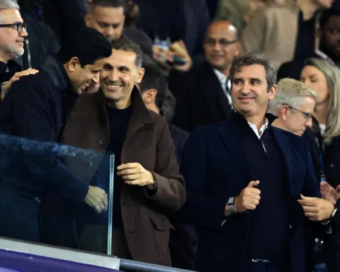 Manchester City-functionarissen staan lachend in de tribune tijdens een wedstrijd.