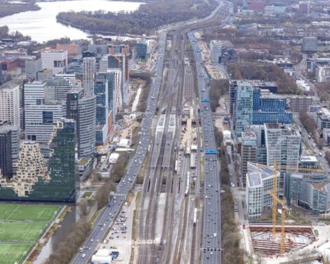 Luchtfoto van de Zuidas in Amsterdam met spoorlijnen, wegen, kantoren en werkzaamheden langs het Zuidasdok-traject.