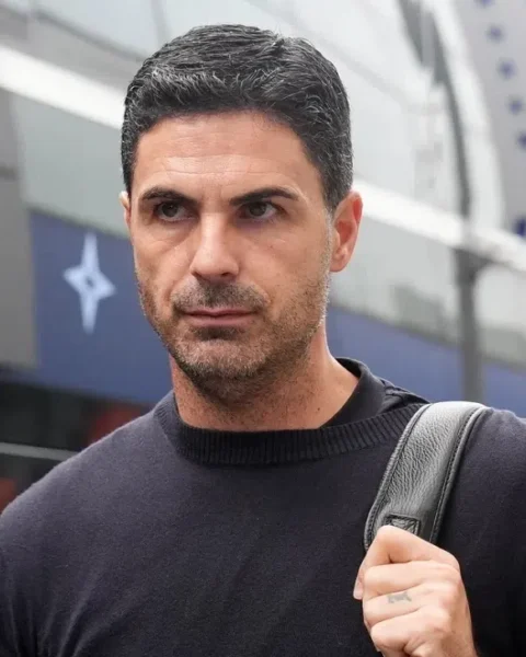 Mikel Arteta loopt buiten een Arsenal-locatie met een tas over zijn schouder.