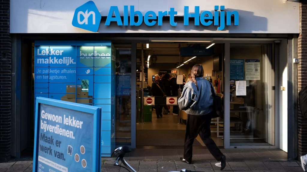 Gevel van een Albert Heijn-winkel met de ingang open en een klant die naar binnen loopt.