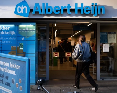 Gevel van een Albert Heijn-winkel met de ingang open en een klant die naar binnen loopt.
