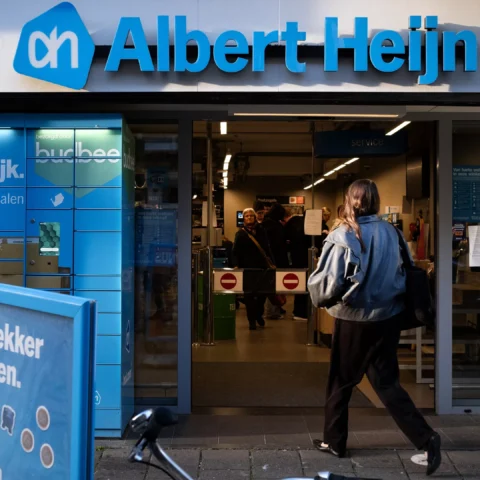 Gevel van een Albert Heijn-winkel met de ingang open en een klant die naar binnen loopt.