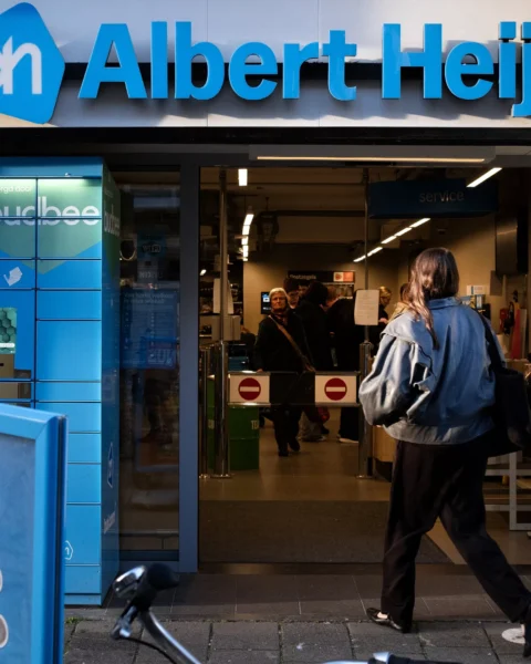 Gevel van een Albert Heijn-winkel met de ingang open en een klant die naar binnen loopt.