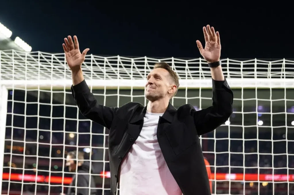 Luuk de Jong zwaait met beide handen omhoog voor een doelnet in een stadion.