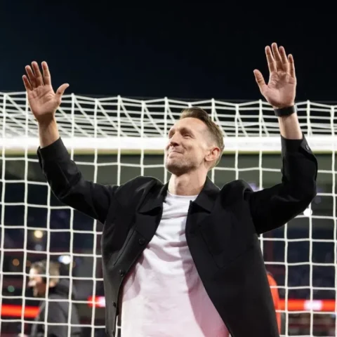 Luuk de Jong zwaait met beide handen omhoog voor een doelnet in een stadion.