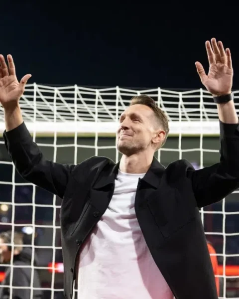 Luuk de Jong zwaait met beide handen omhoog voor een doelnet in een stadion.