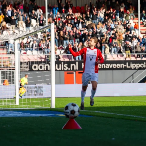 Voetballer van FC Emmen juicht naast het doel terwijl de doelman van Almere City toekijkt.