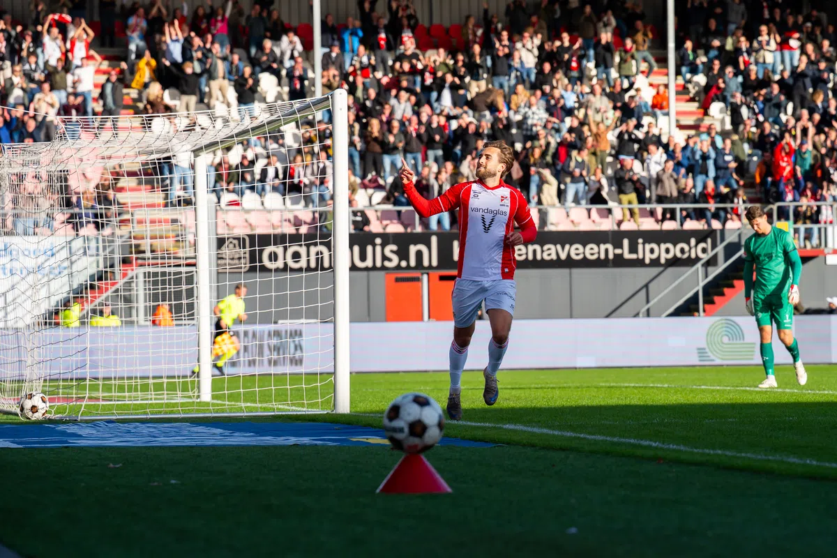 Voetballer van FC Emmen juicht naast het doel terwijl de doelman van Almere City toekijkt.